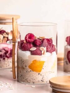 3 jars of overnight oats with frozen fruit, topped with fresh raspberries and toasted flaked almonds.