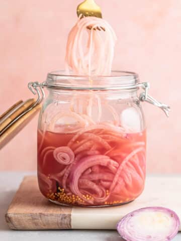 No cook quick pickled red onions being scooped out of a jar with a fork.