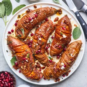 Hasselback sweet potatoes in a bed of brown butter and cranberry topping.