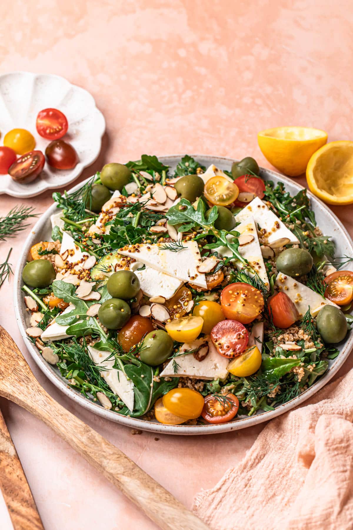 Arugula quinoa salad with feta, olives and cherry tomatoes on a large plate.