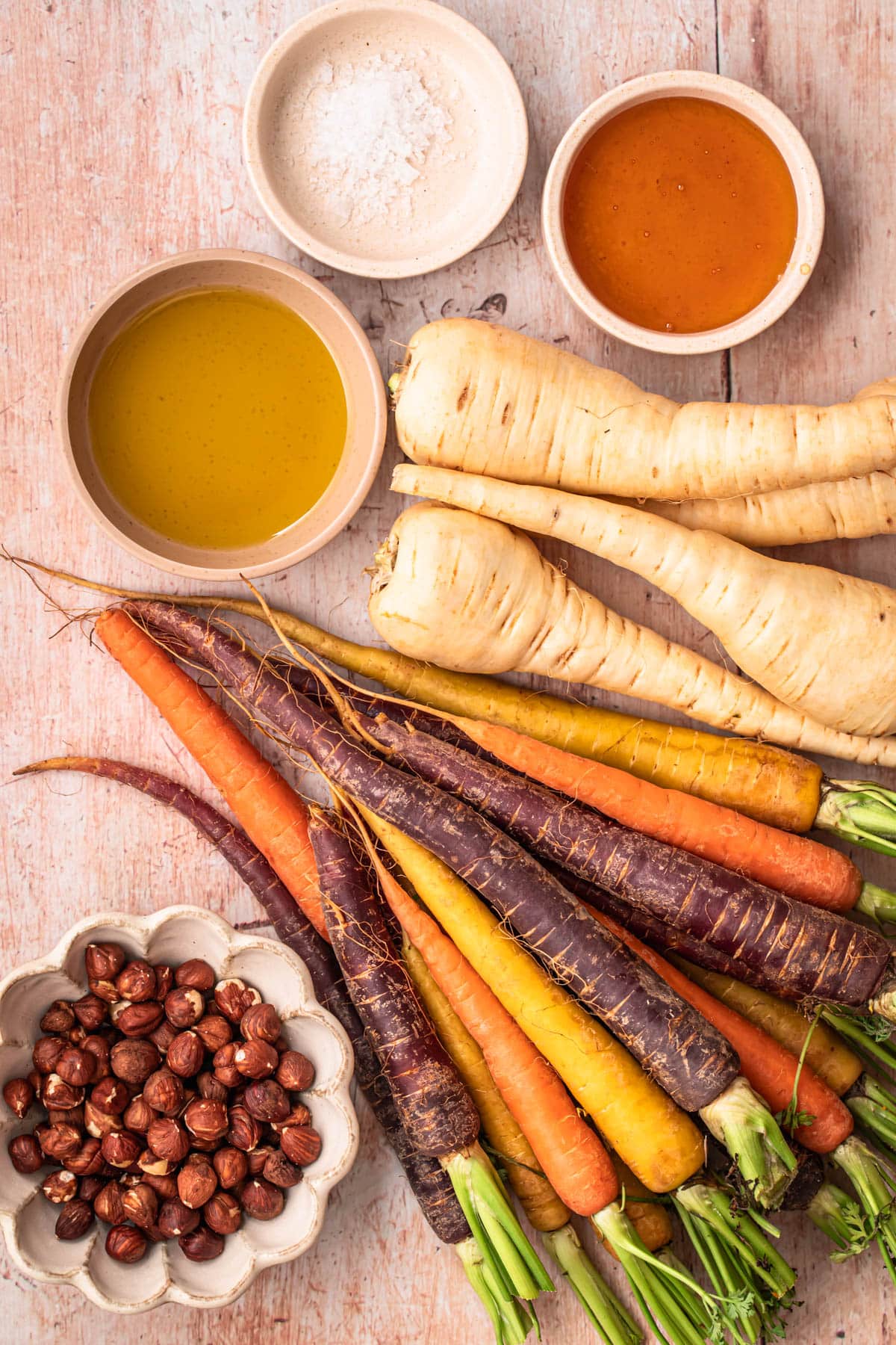 Ingredients for honey roasted parsnips and carrots laid out in individual bowls.
