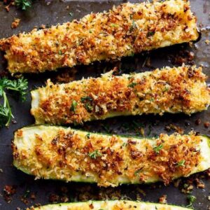 Zucchini covered with parmesan topping with baked cheese topping sprinkled around.