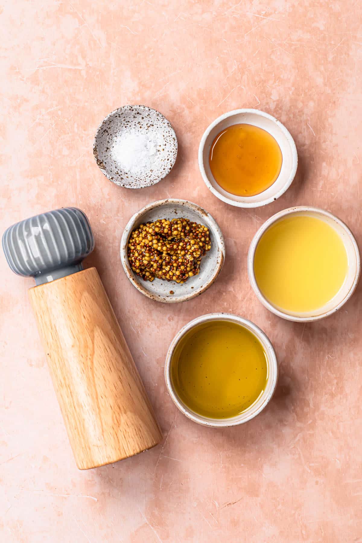 Ingredients for wholegrain mustard dressing laid out in individual bowls.