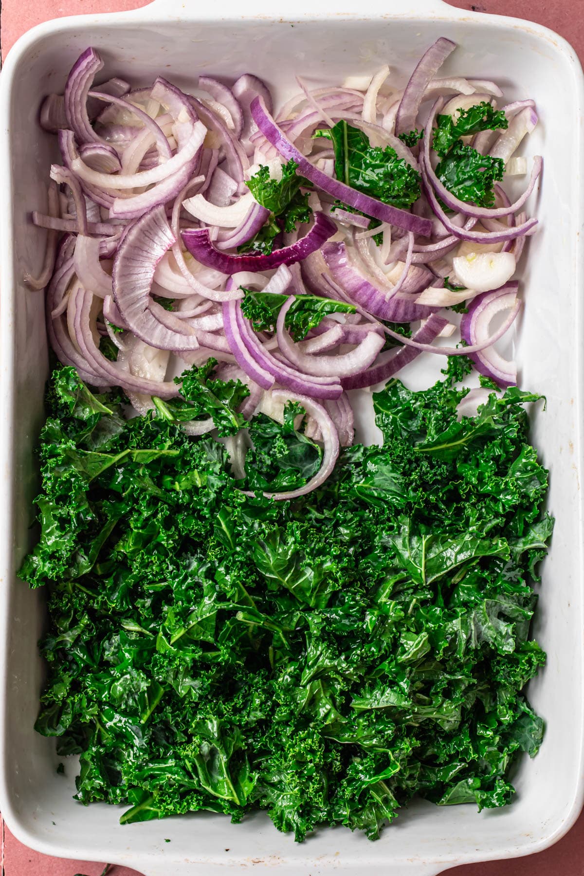 Kale and purple onion on a large baking dish.