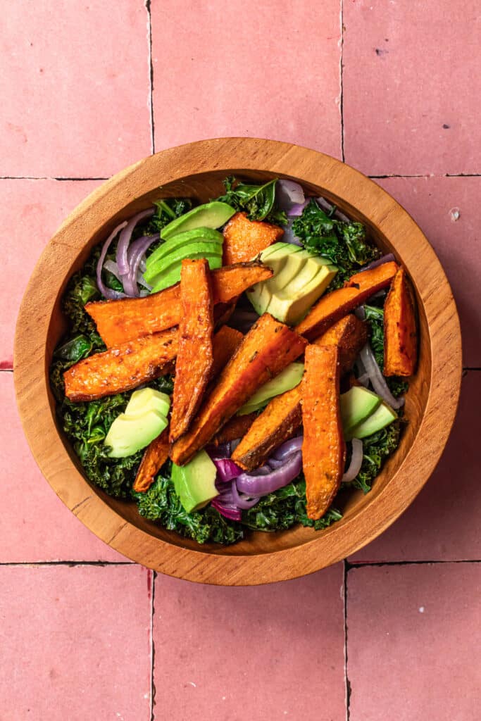 Kale and red onion topped with avocado and roasted sweet potato.