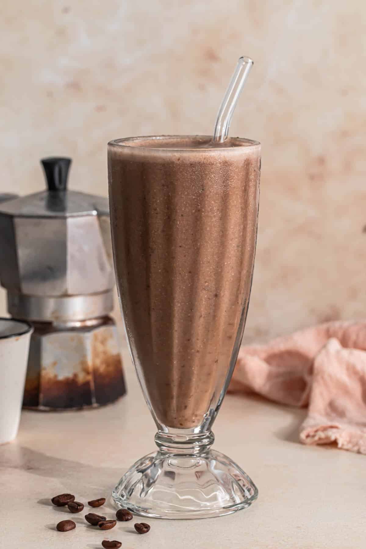 Espresso smoothie in a tall milkshake glass with a glass straw.