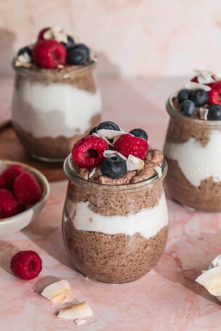 Flaxseed pudding layered with yoghurt in a small jar, topped with berries and coconut.