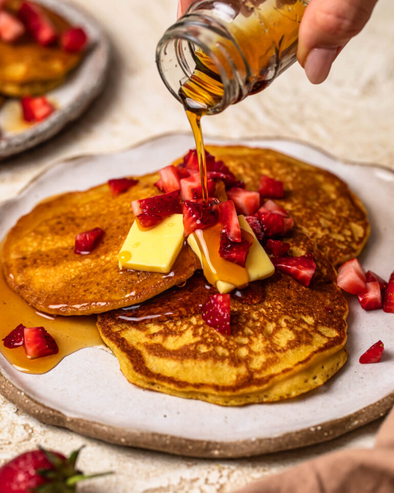 Maple syrup being poured over almond flour pumpkin pancakes.