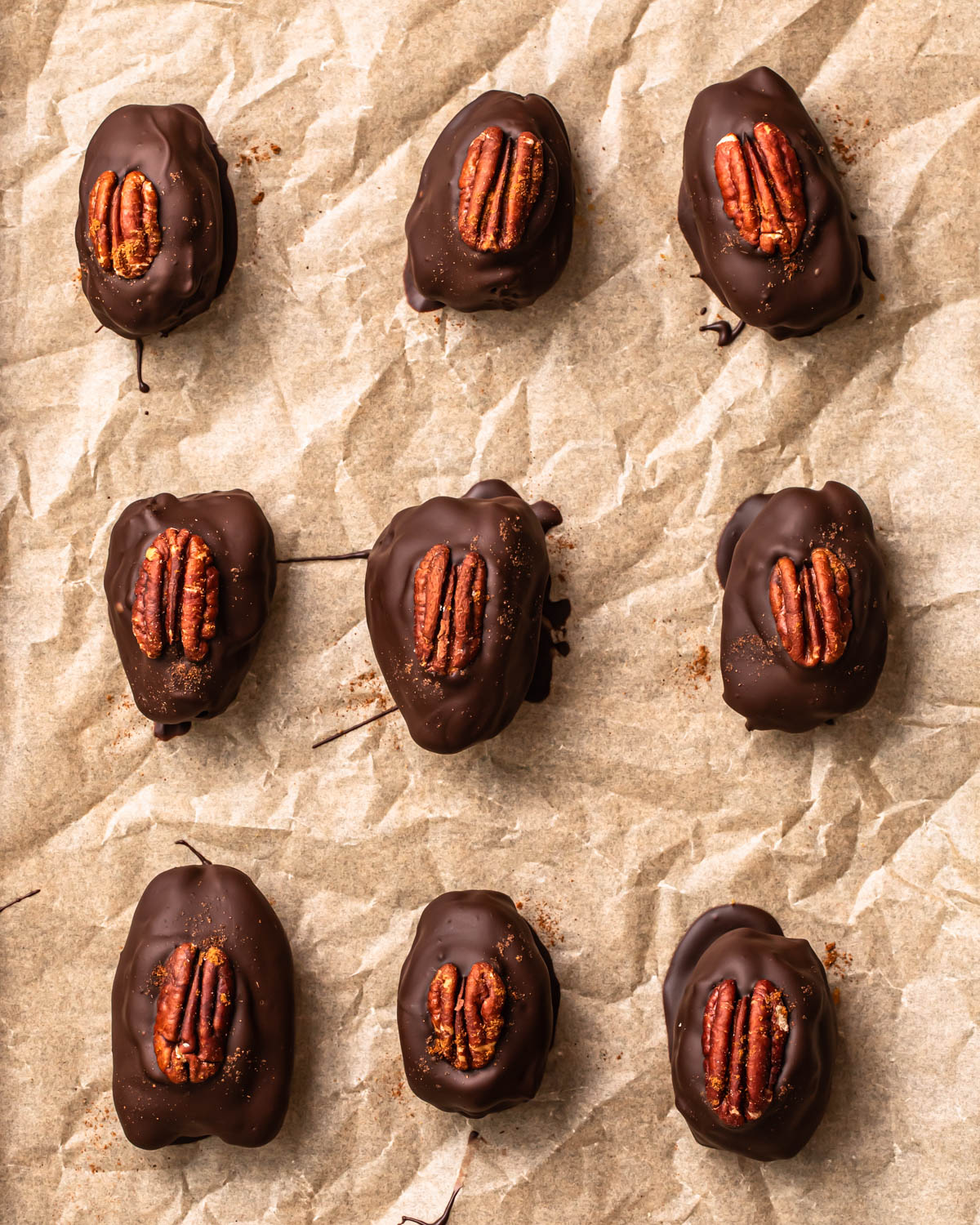 Pecan pie stuffed dates laid out on a parchment paper lined baking tray.