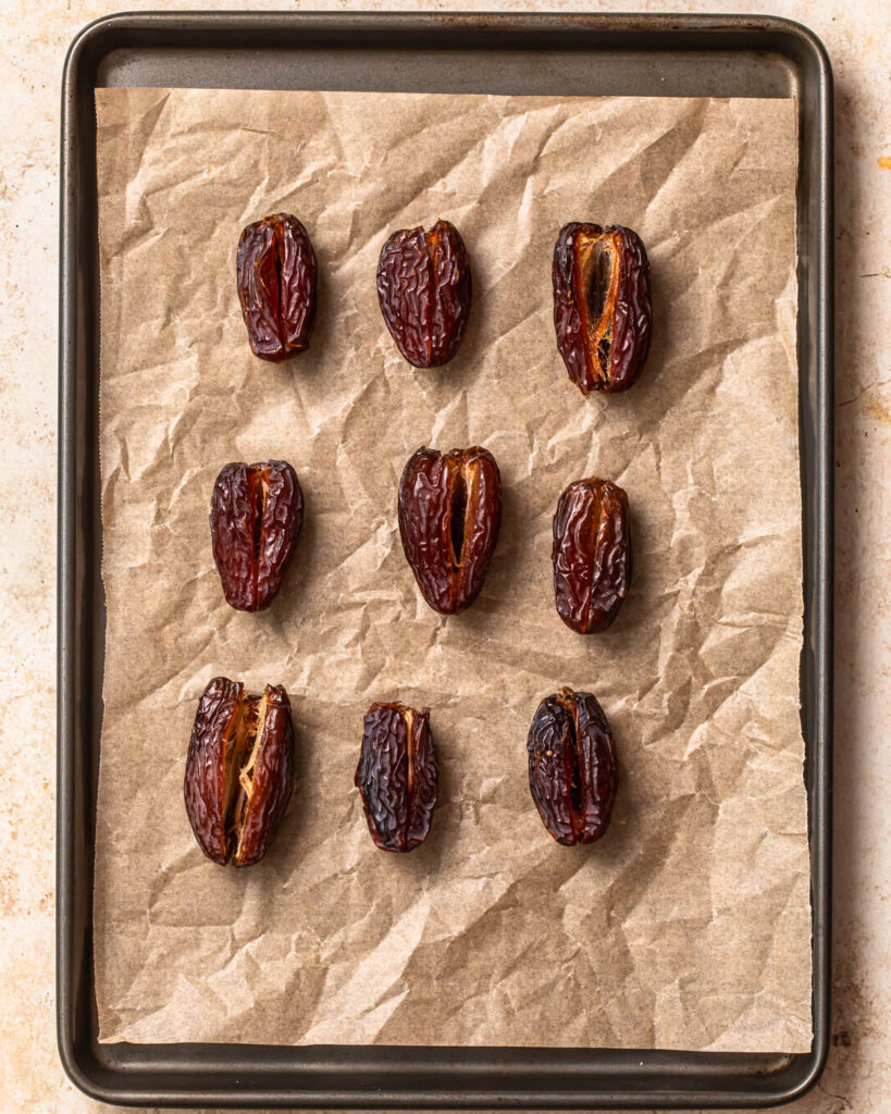Medjool dates lined up on a tray with pits removed.