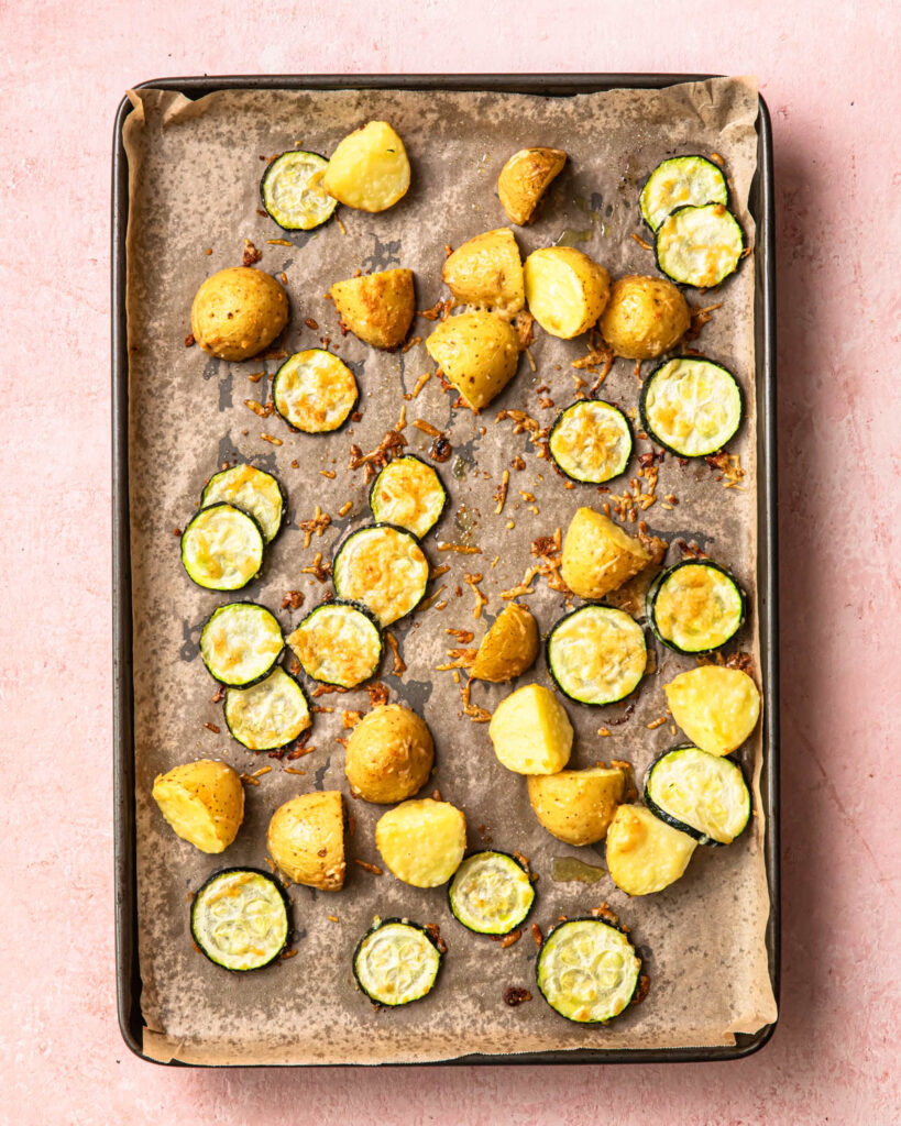 Roasted seasoned potatoes and zucchini on a sheet pan.