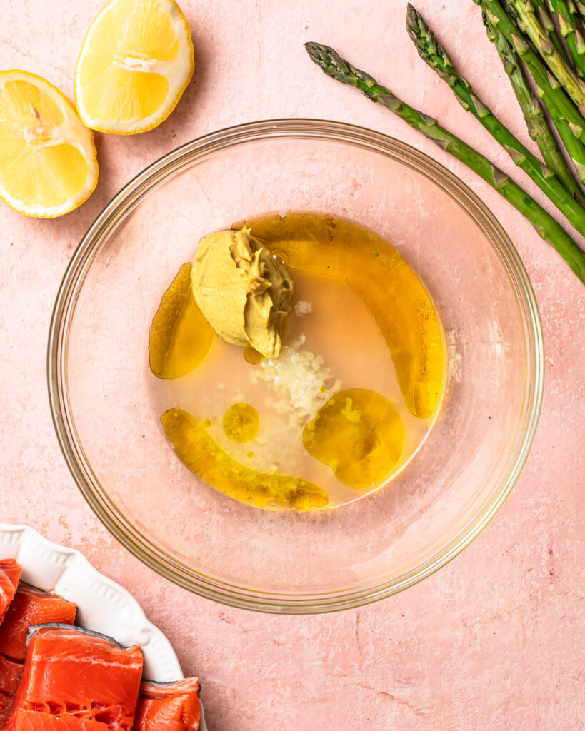Ingredients for lemon dijon marinade in a glass mixing bowl. 
