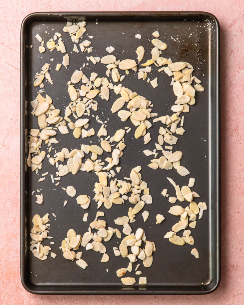 Flaked almonds spread out on a baking tray.
