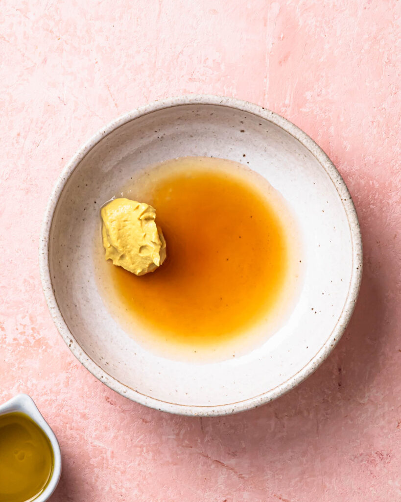 Ingredients for maple dijon dressing in a bowl. 