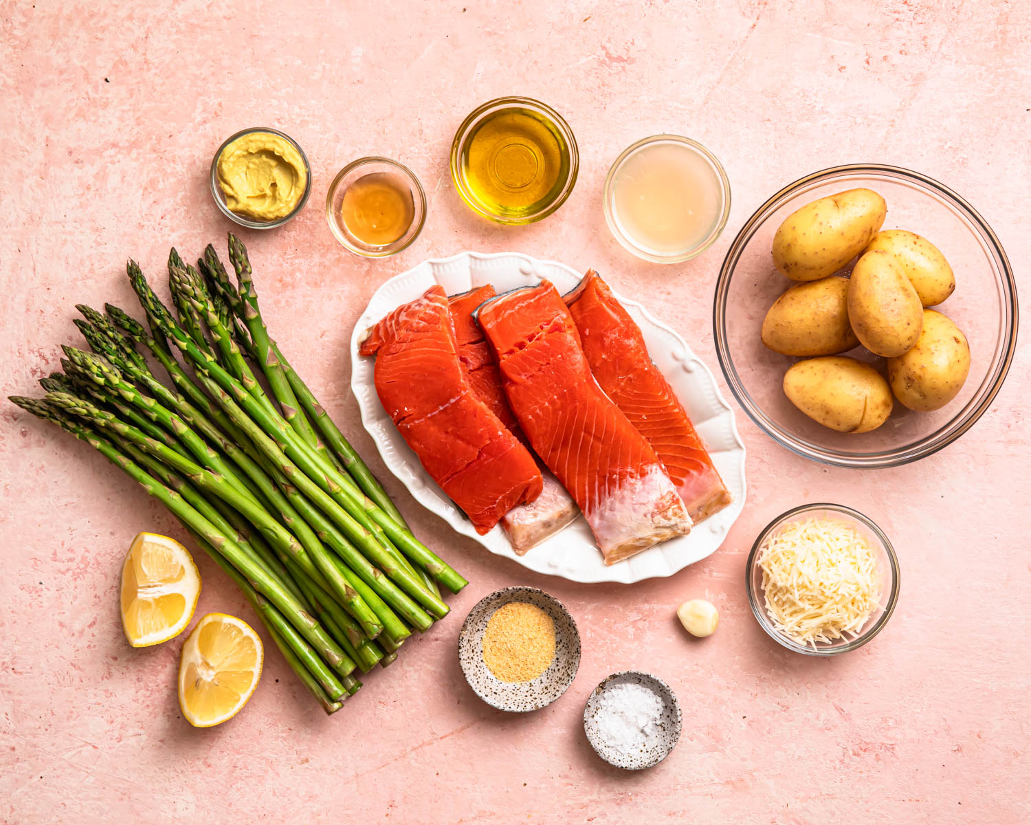 Ingredients for sheet pan salmon and asparagus laid out in individual bowls.
