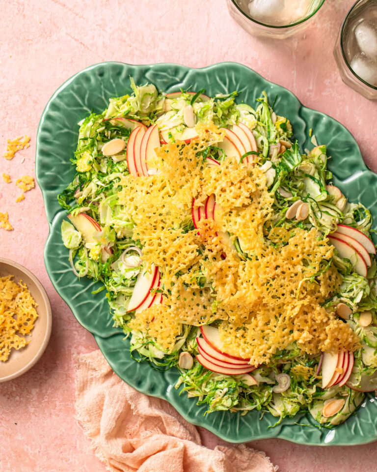Shaved Brussels sprout salad topped with parmesan crisps on a serving platter.