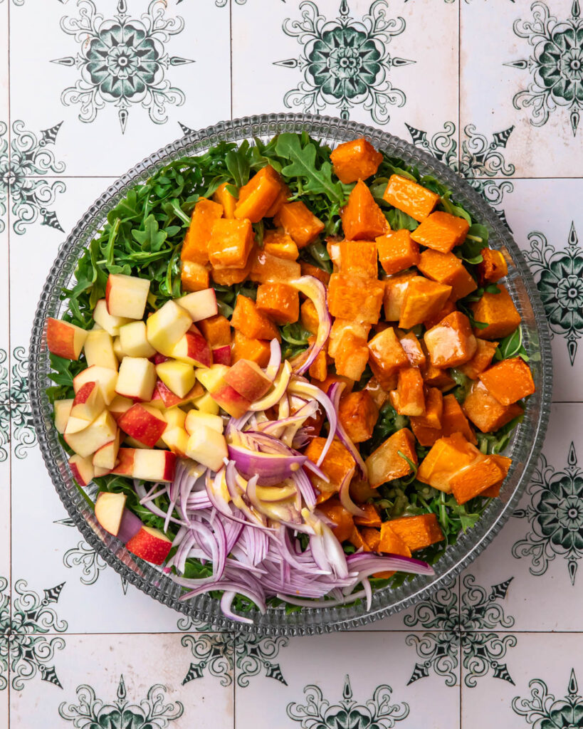 Components of butternut squash and feta salad in a salad bowl. 
