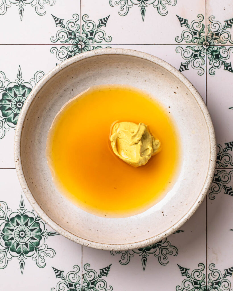 Ingredients for orange dijon dressing added to a bowl. 