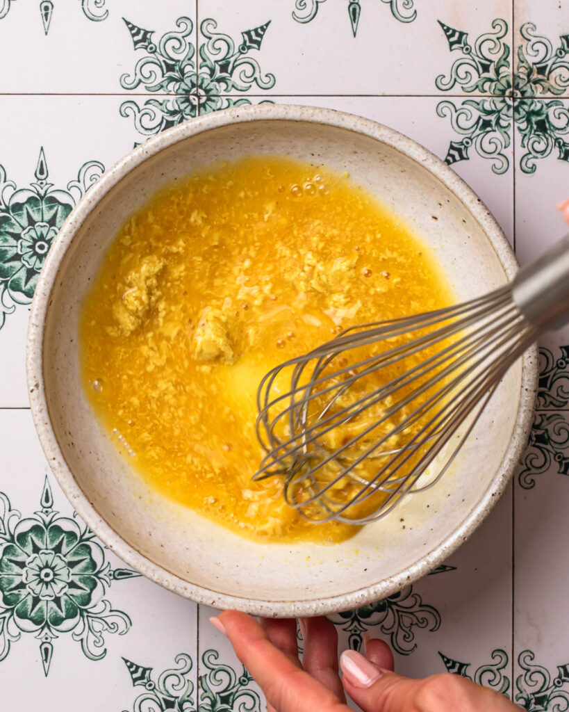 Ingredients for salad dressing being whisked together in a bowl.