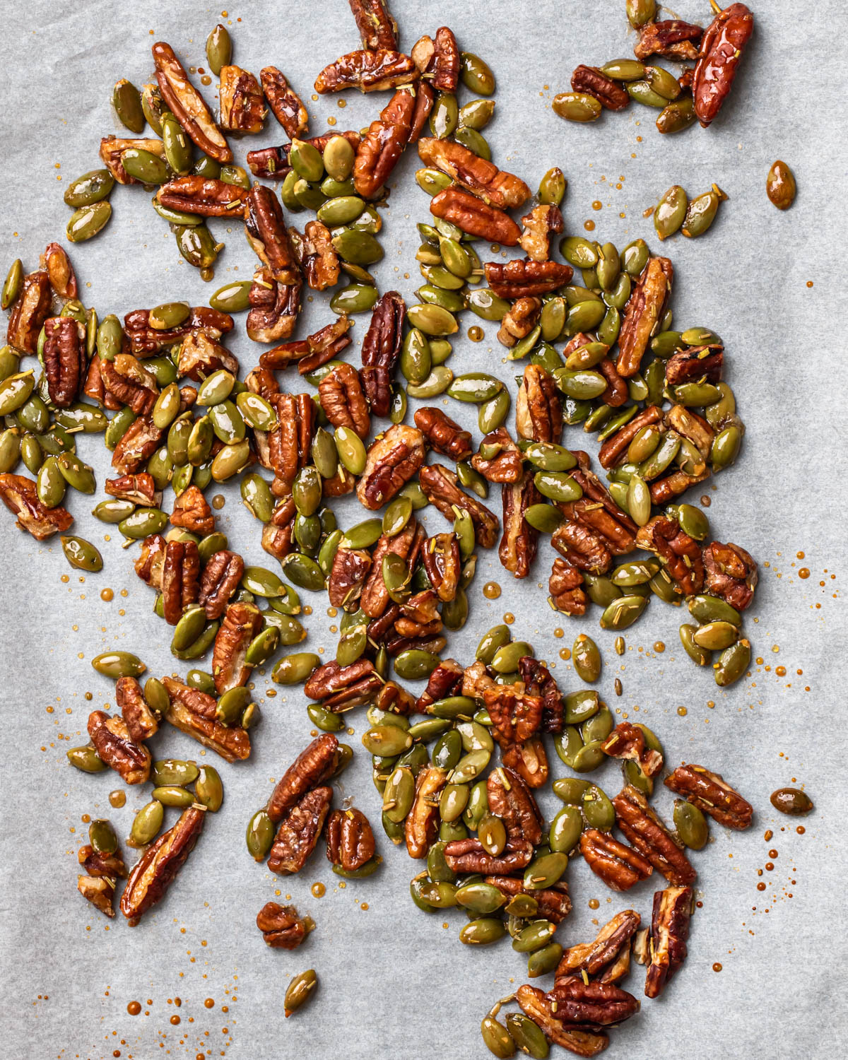 Honey candied pecans and pumpkin seeds on a baking sheet.
