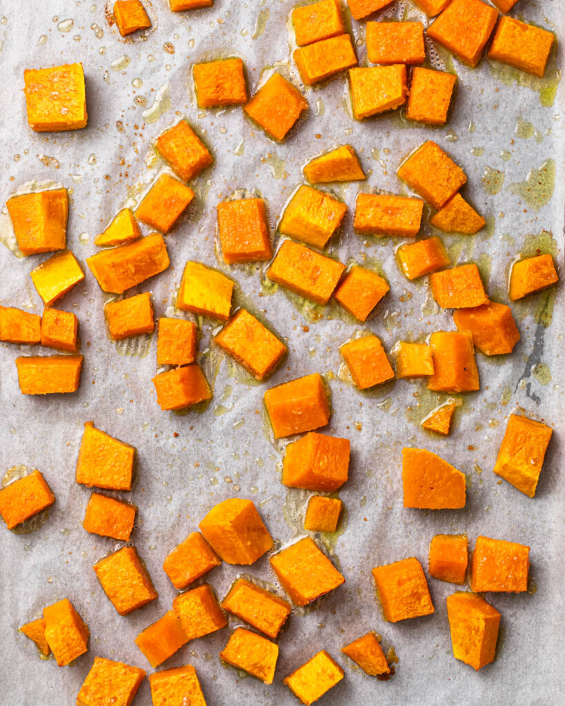 Close up of roasted butternut squash cubes on a baking sheet.