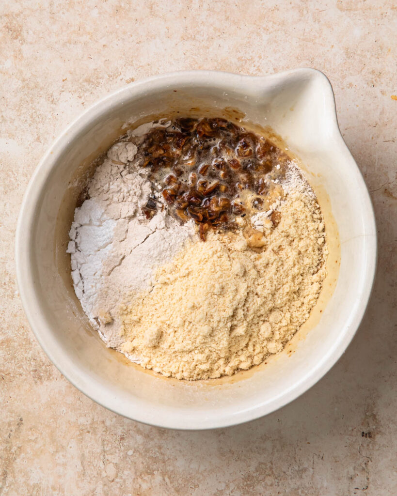 Dry ingredients and softened dates added to the wet ingredients in a large mixing bowl to make gluten free sticky date pudding.