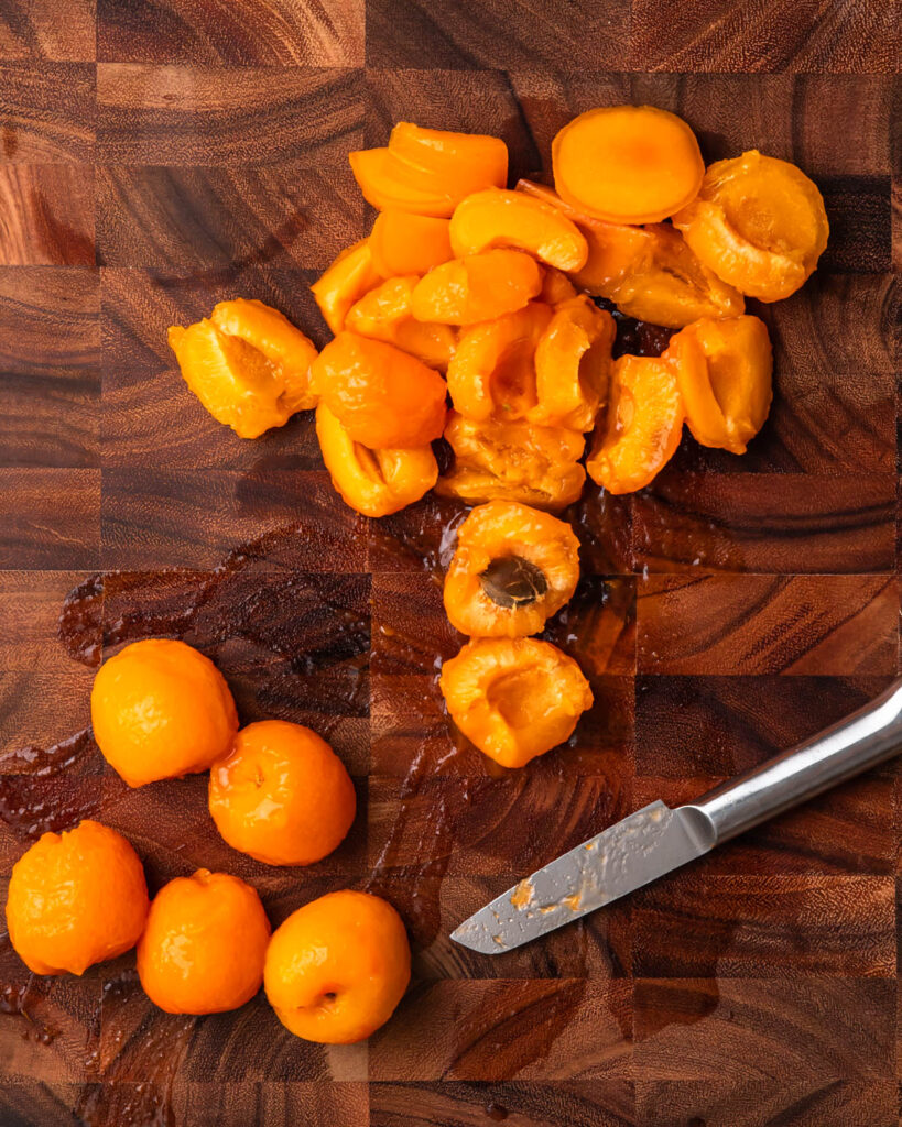 Peeled apricots roughly chopped on a board.