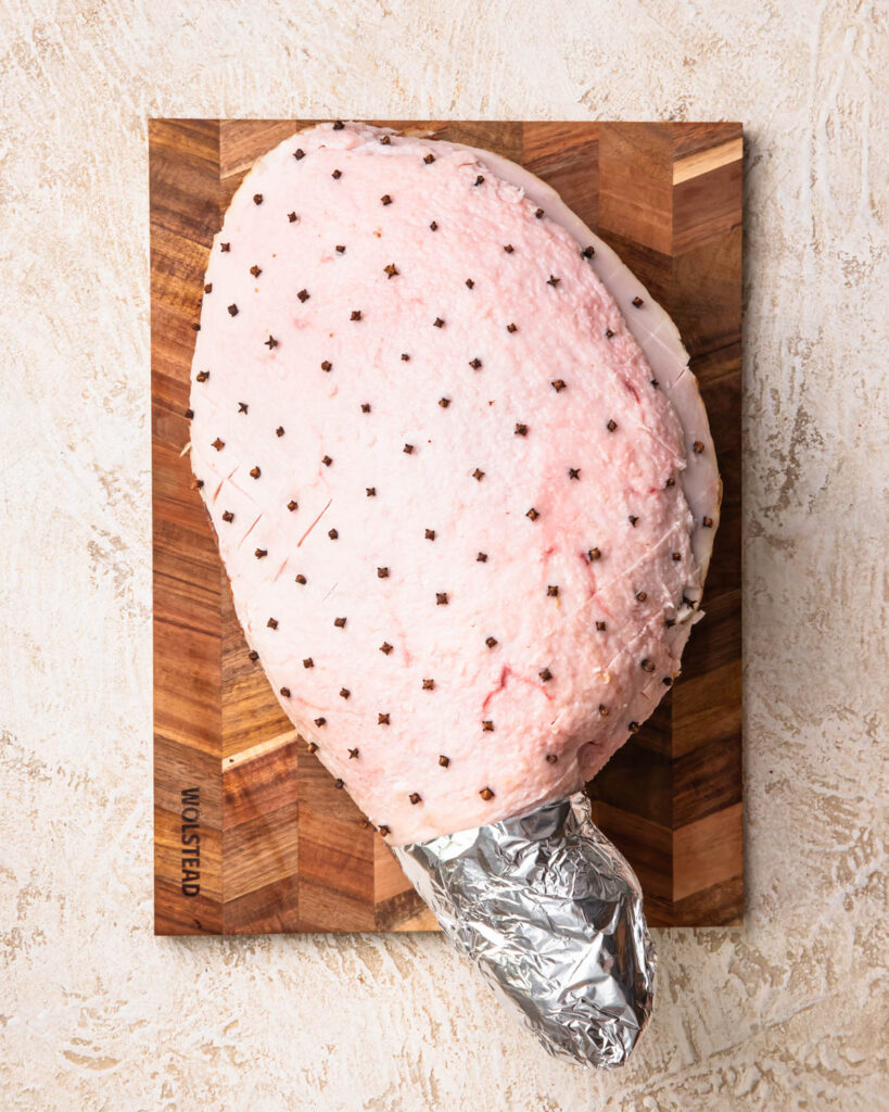 A full leg ham with skin removed, fat scored and cloves inserted into the fat into each diamond.