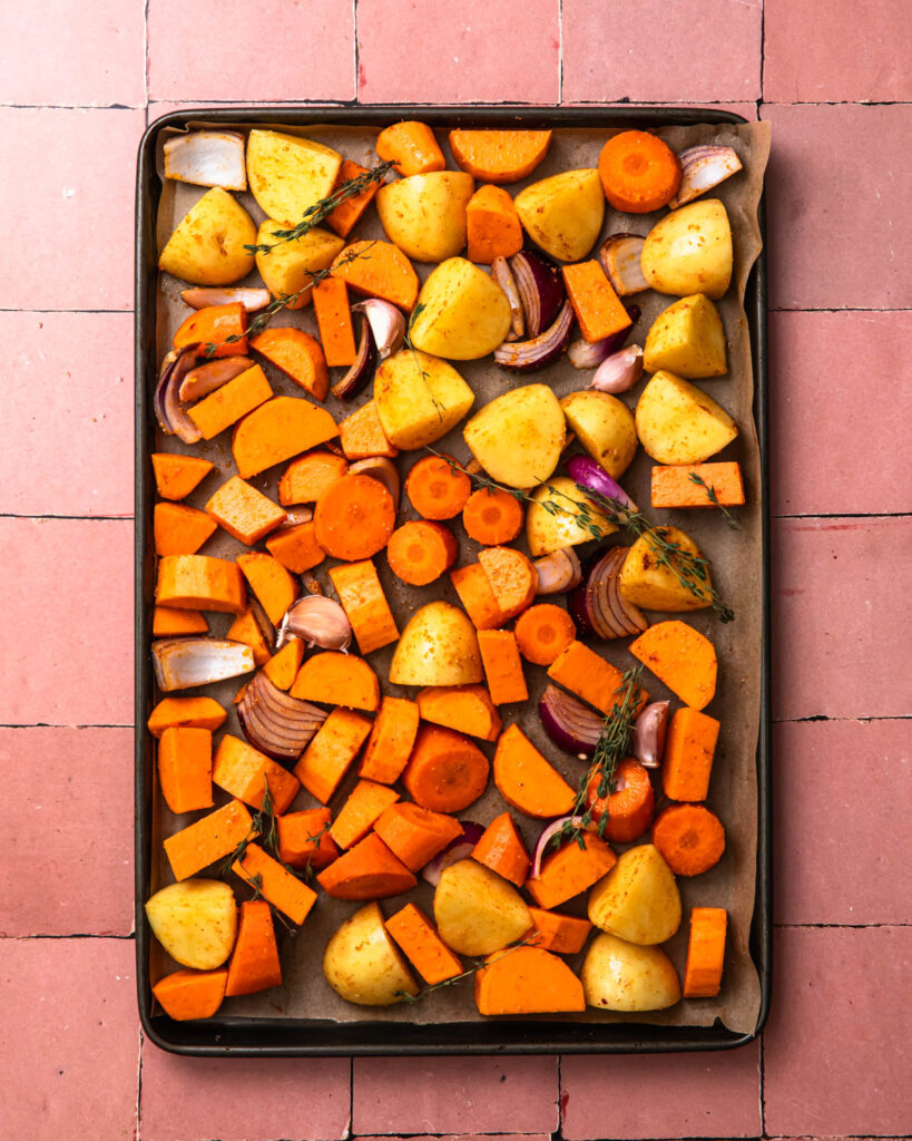 Seasoned vegetables spread out on a large sheet pan.