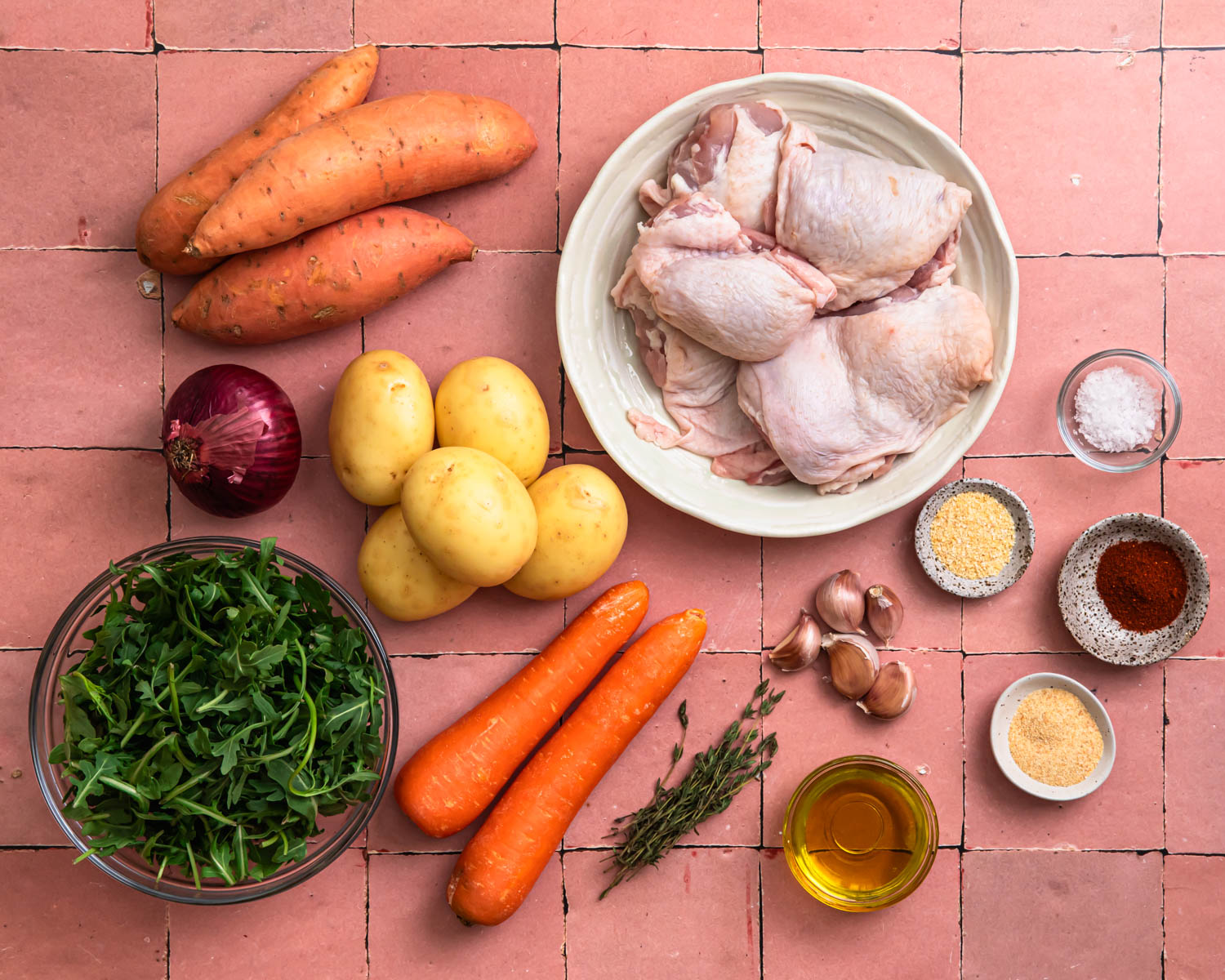 Ingredients for sheet pan chicken thighs and vegetables laid out in individual bowls. 