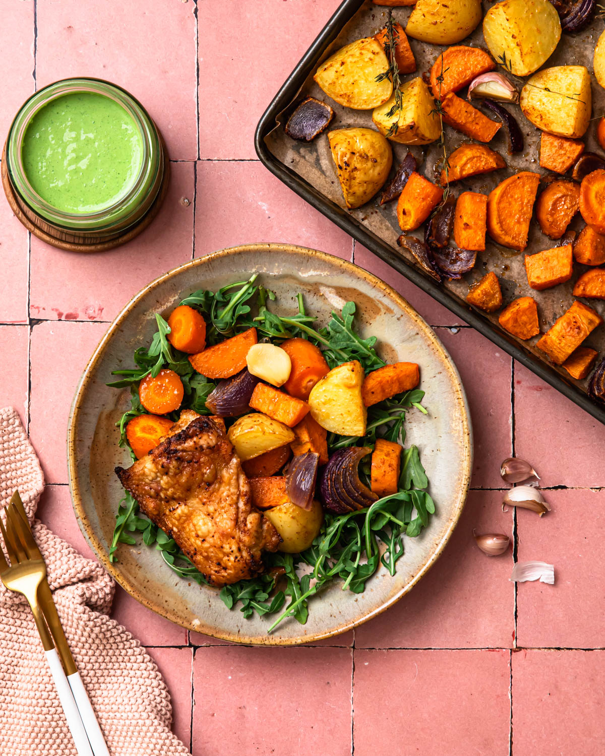 Sheet pan chicken thighs and vegetables presented on a plate over fresh greens.