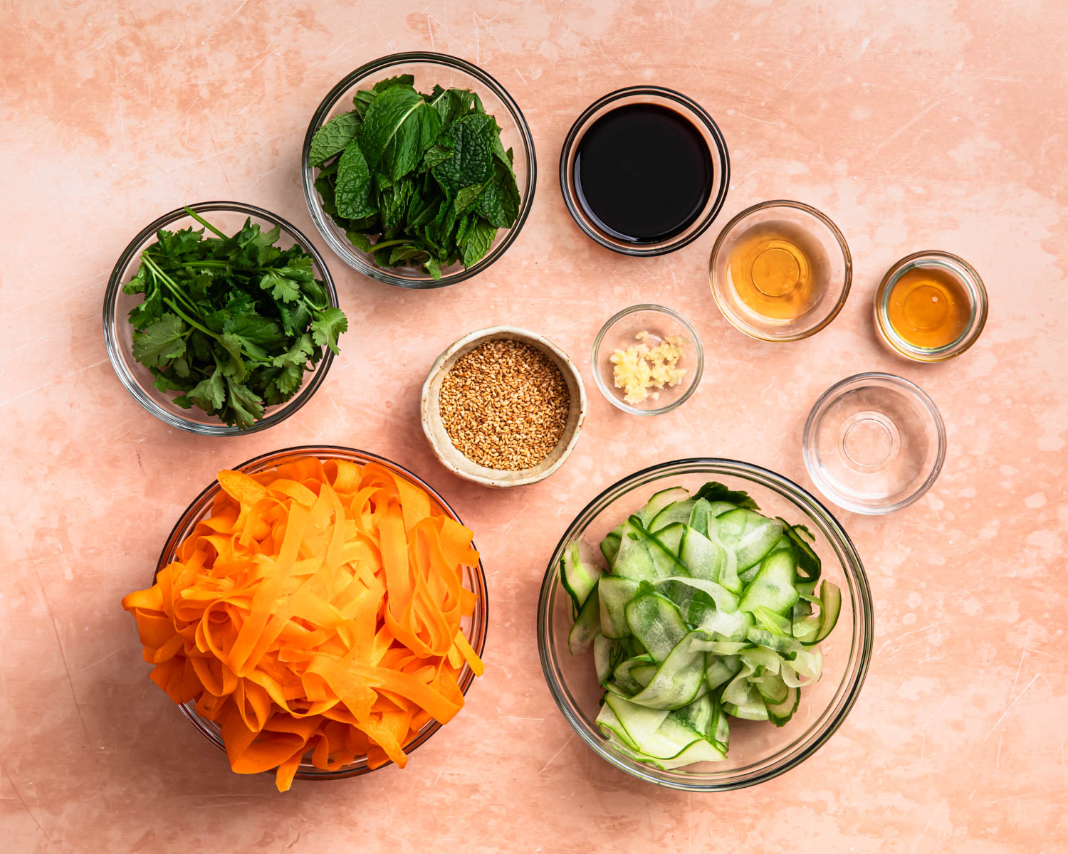 Ingredients for Asian Carrot Cucumber Salad laid out in individual bowls. 