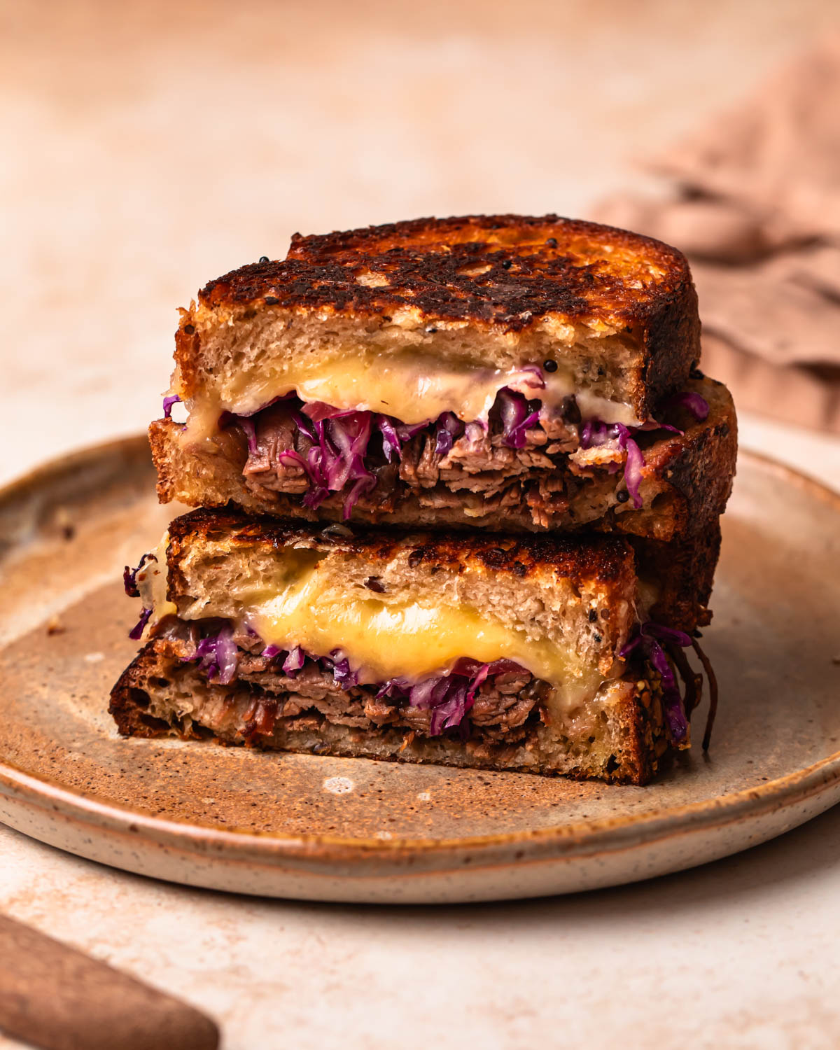 A brisket grilled cheese sliced in half and stacked on a plate.