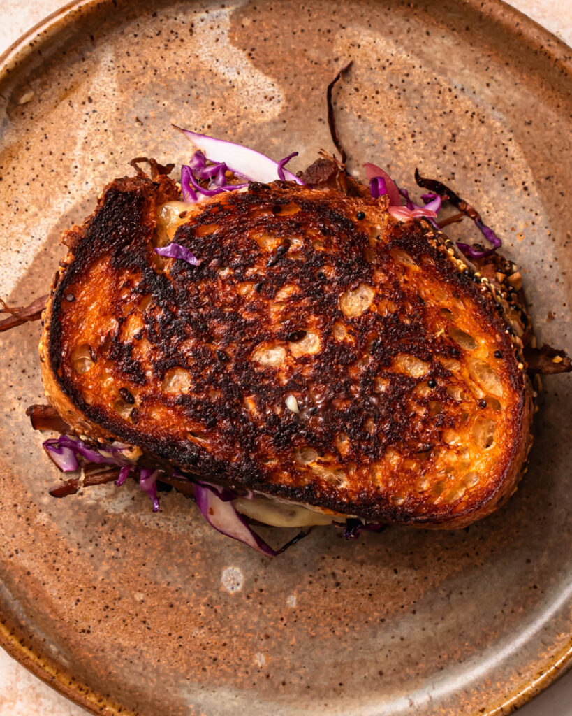 A golden brown brisket grilled cheese sandwich on a plate.