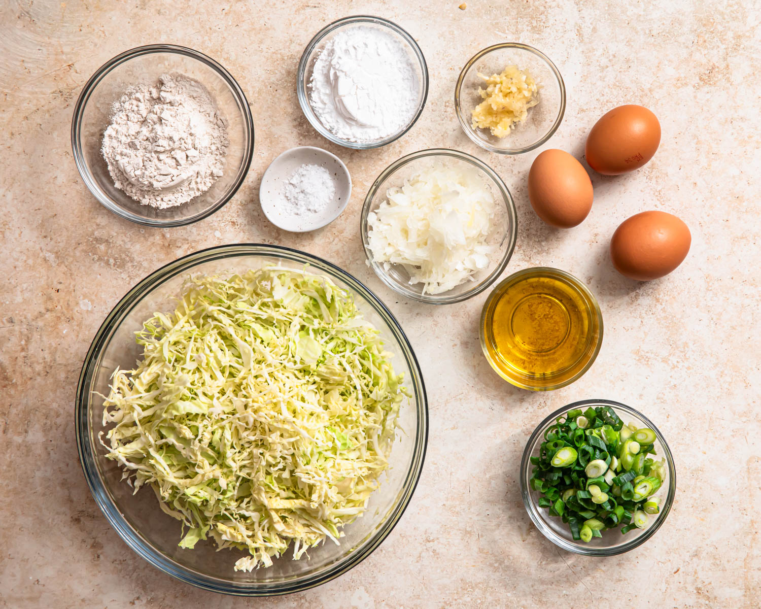 Ingredients for cabbage fritters laid out in individual bowls. 