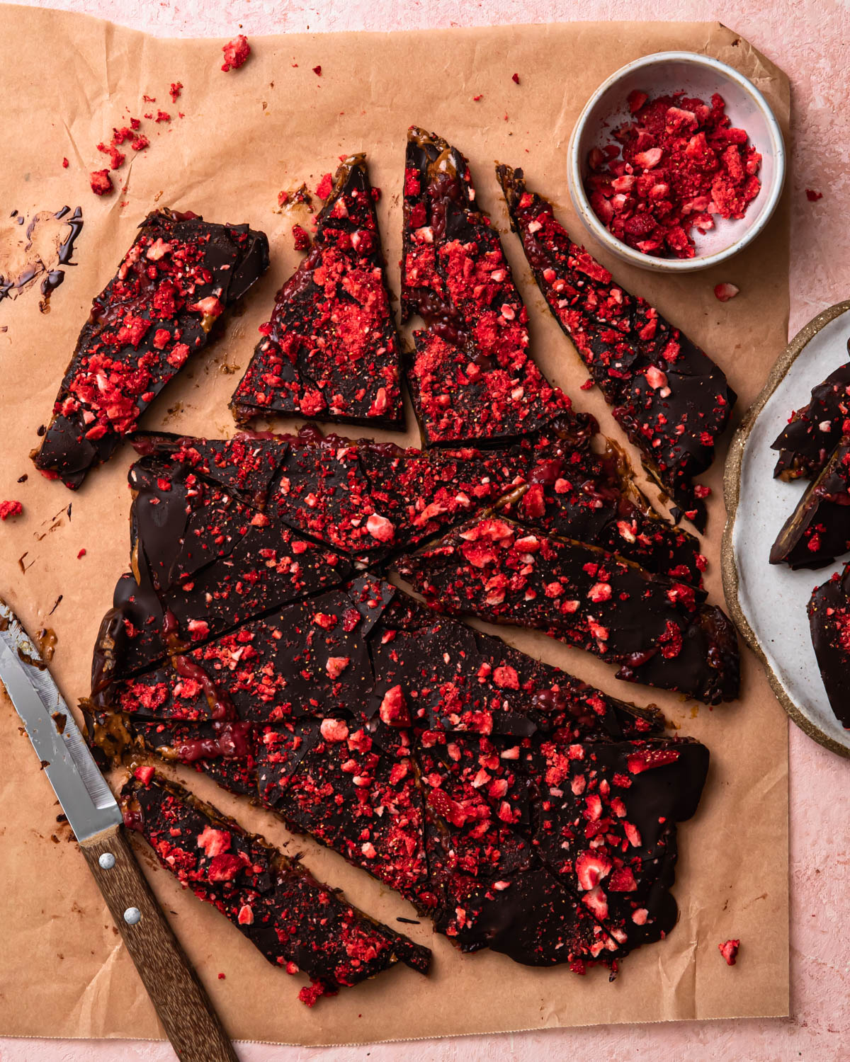 Dark chocolate date bark topped with freeze dried strawberries and chopped into pieces.