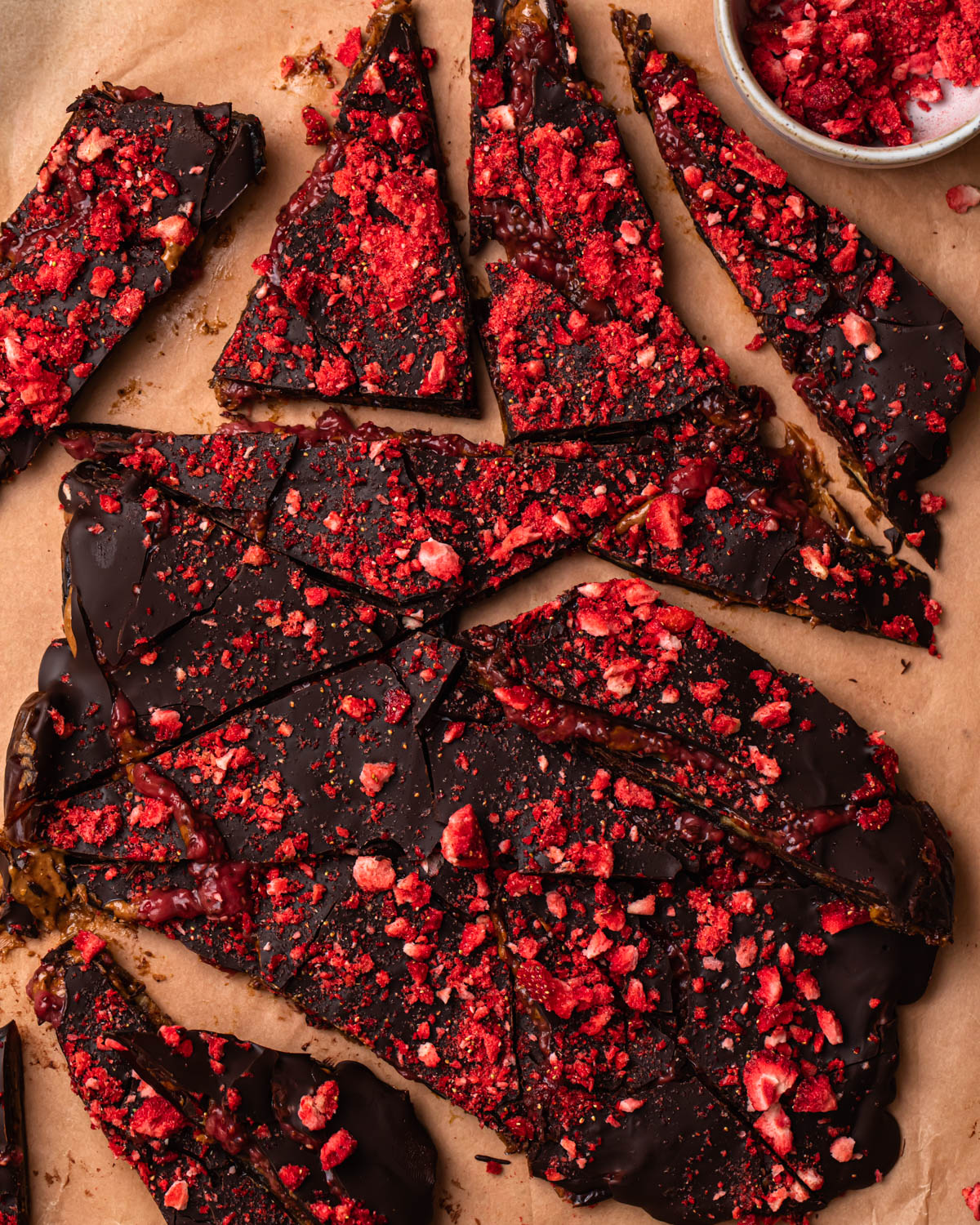 Dark chocolate date bark topped with freeze dried strawberries and chopped into pieces.