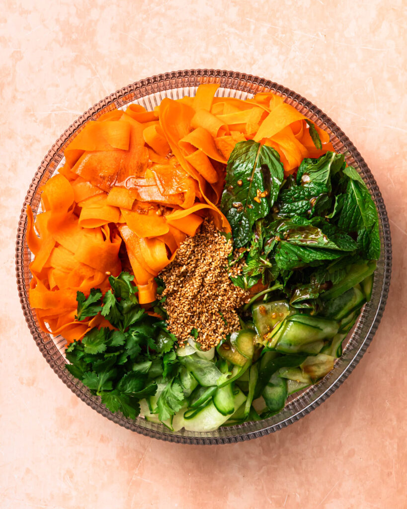 Ingredients for Asian Carrot Cucumber Salad in a mixing bowl.