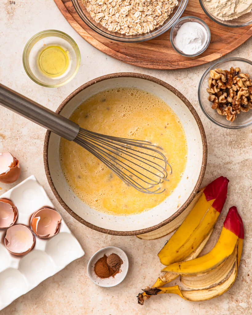 Wet ingredients for banana bread baked oats mixed together in a mixing bowl. 