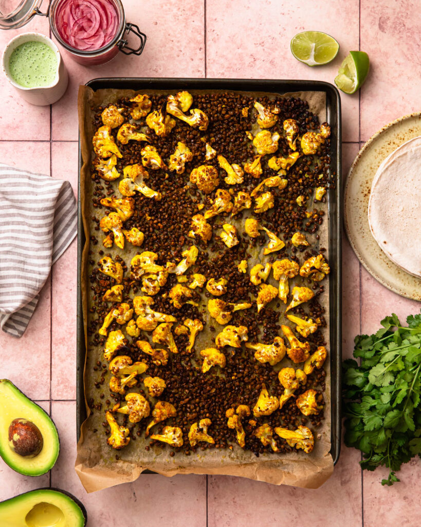 Roasted cauliflower and lentils on a baking tray.