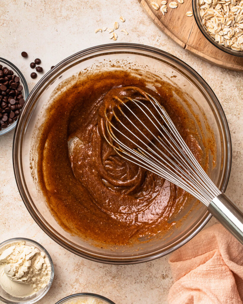 Wet ingredients for oat energy balls being whisked in a glass mixing bowl. 