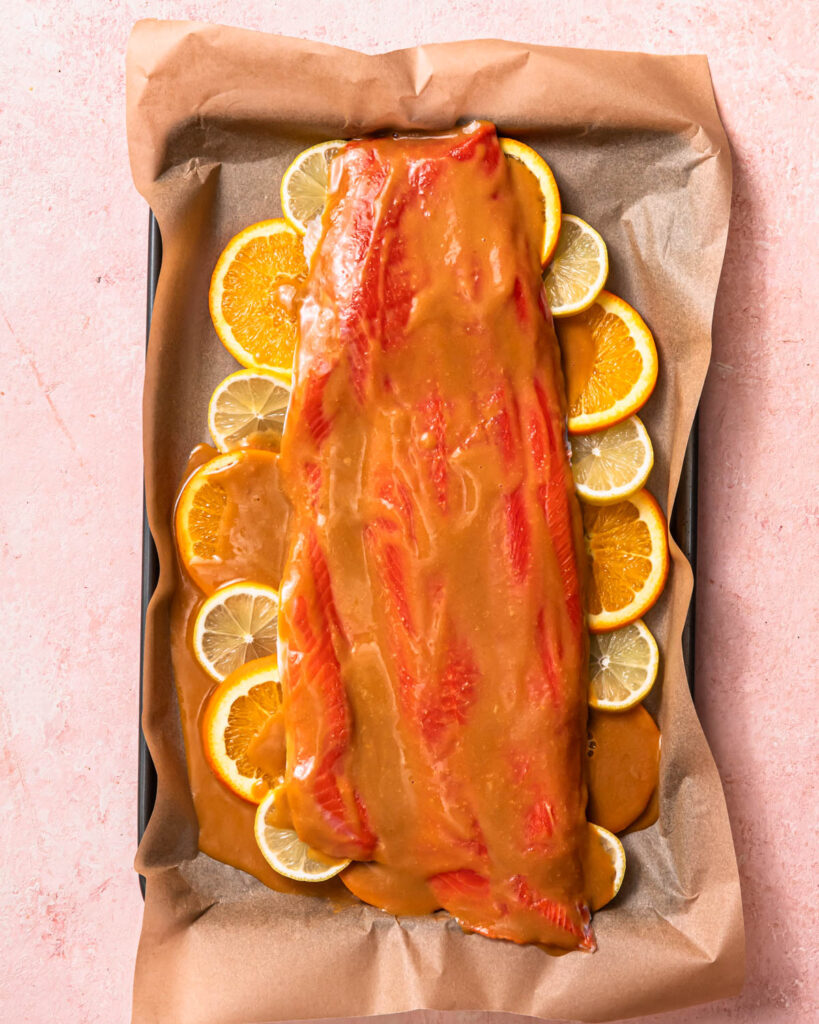 Salmon coated in a citrus miso butter sauce resting on top of slices of orange and lemon.