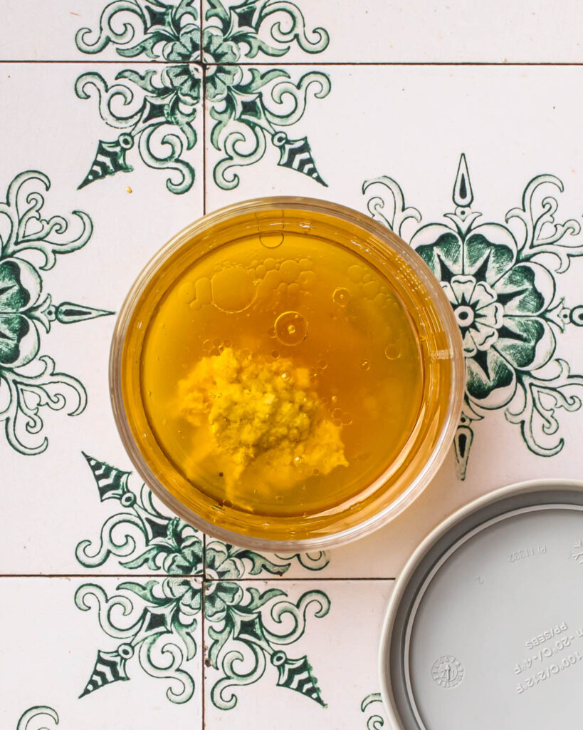 Ingredient for salad dressing added to a small glass jar. 