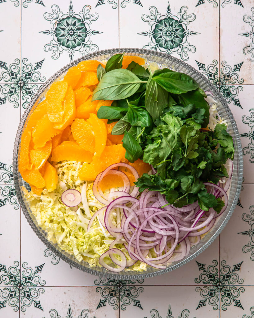 Ingredient for citrus slaw added to a large glass bowl. 