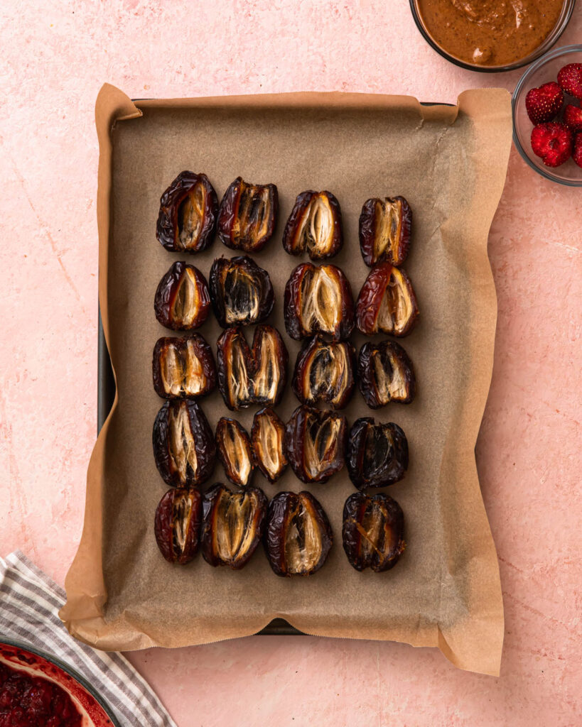 Pitted dates lined up on a baking tray.