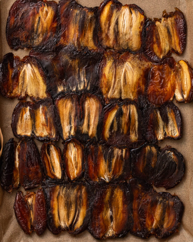 Rolled medjool dates lined up tray. 