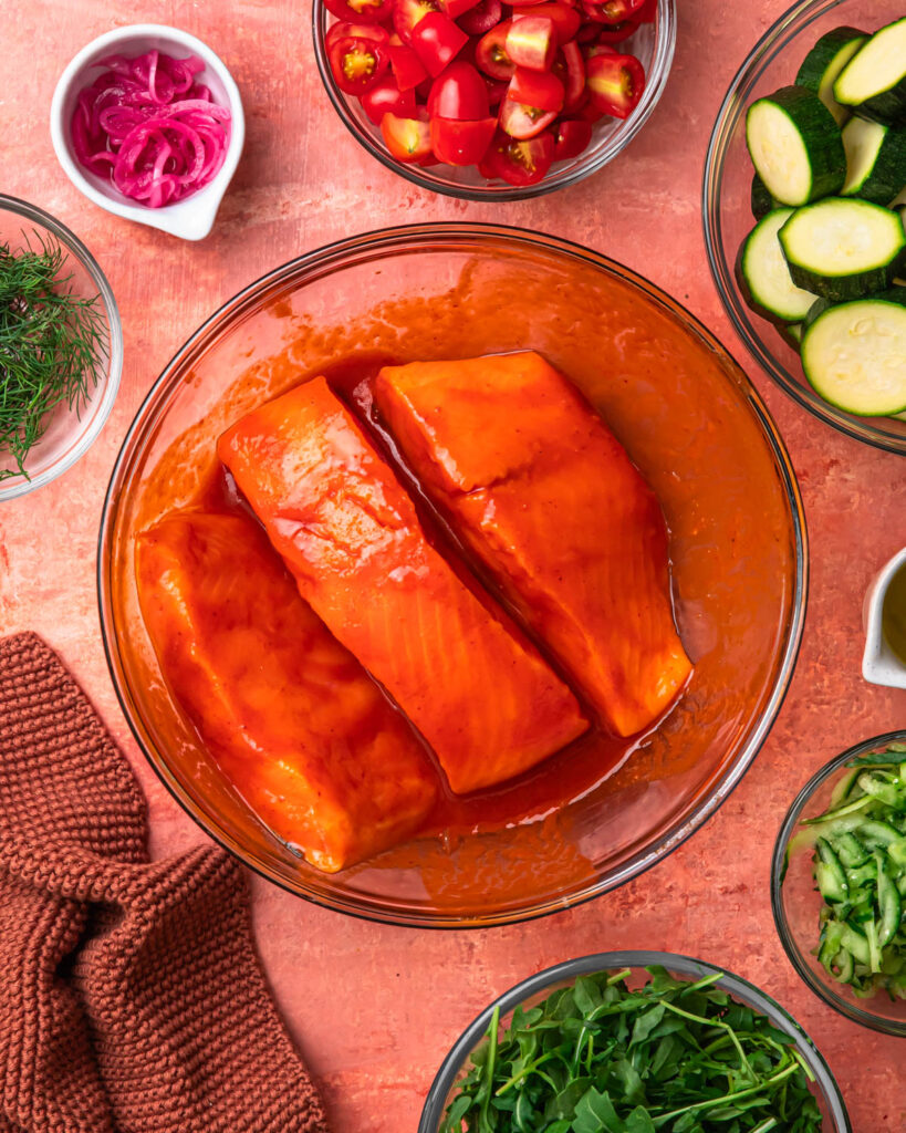 Salmon marinaded in a harissa honey sauce in a bowl.