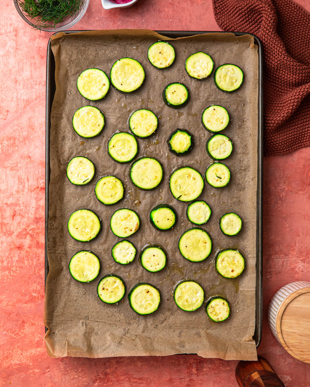 Seasoned zucchini rounds on a baking tray