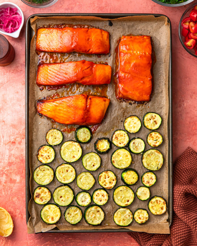 Roasted harissa honey salmon and zucchini on a baking tray.