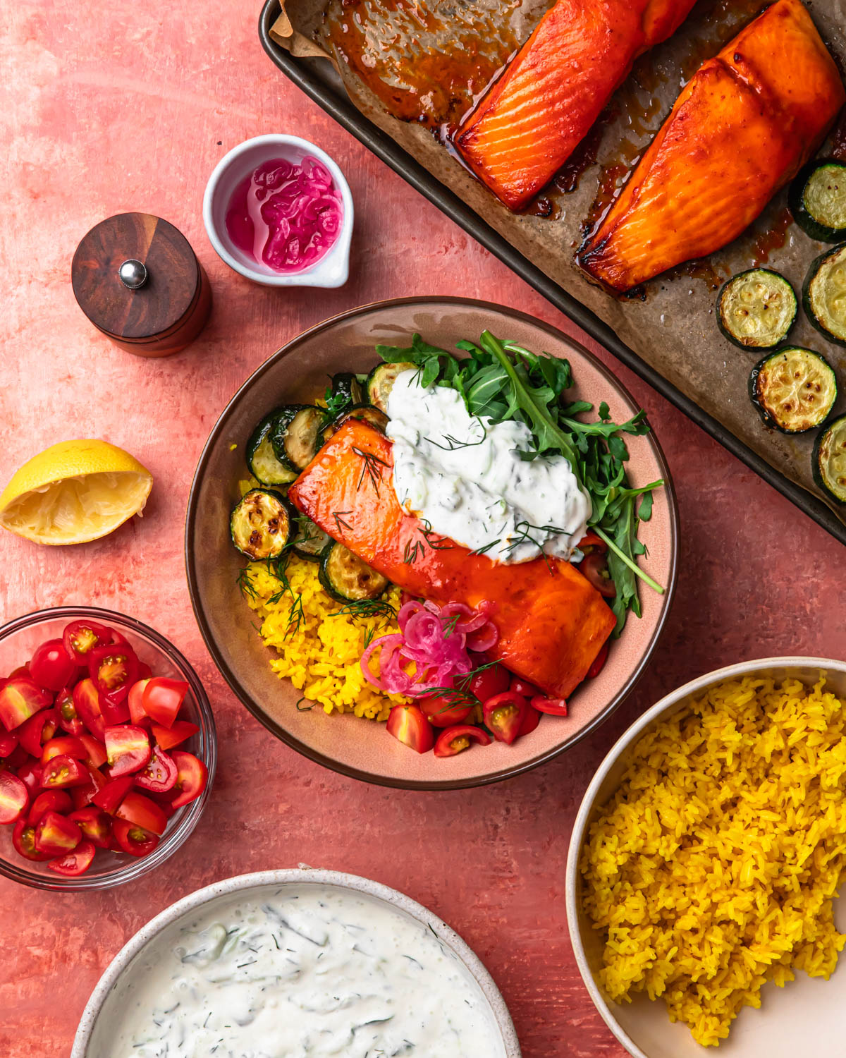 A harissa honey salmon rice bowl surrounded by all of the individual components to make it.